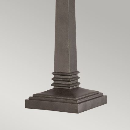 Stĺpiková základňa stola stojí na štvorcovej podstave. Základňa je tmavosivá a má reliéfne ozdobné prvky pod stĺpikom. Prostredie je neutrálne, svetlé pozadie.