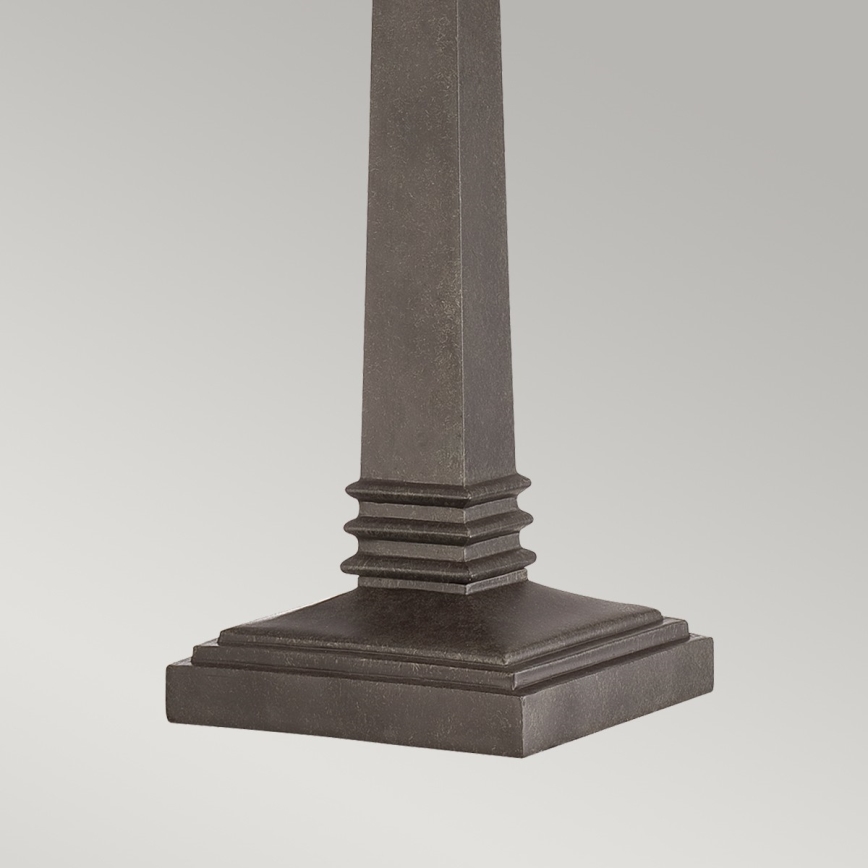 Stĺpiková základňa stola stojí na štvorcovej podstave. Základňa je tmavosivá a má reliéfne ozdobné prvky pod stĺpikom. Prostredie je neutrálne, svetlé pozadie.