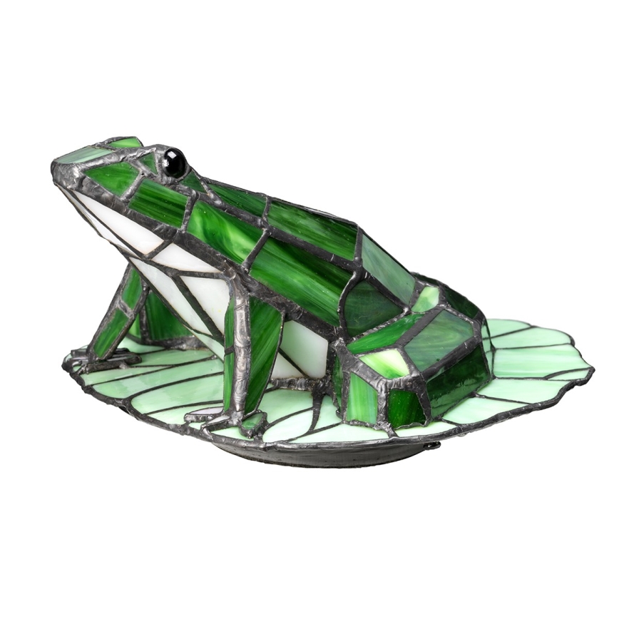 Sklenená žabka z Tiffany skla sedí na liste. Žabka je zelená a biela, zhotovená z malých farebných sklenených štvorcov. Je umiestnená na tmavej podložke v tvare listu.