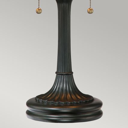 Stolová lampa s tmavosivou kovovou nohou, zakončenou širokou podstavou. Noha má stĺpovitý tvar s ryhovaním a dvoma retiazkami s guľôčkami na zapínanie.