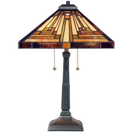 Stolová lampa s štvorcovou tienidlom z farebného skla stojí na tmavom podstavci. Tienidlo je zdobené geometrickým vzorom. Lampa má dva retiazkové vypínače.