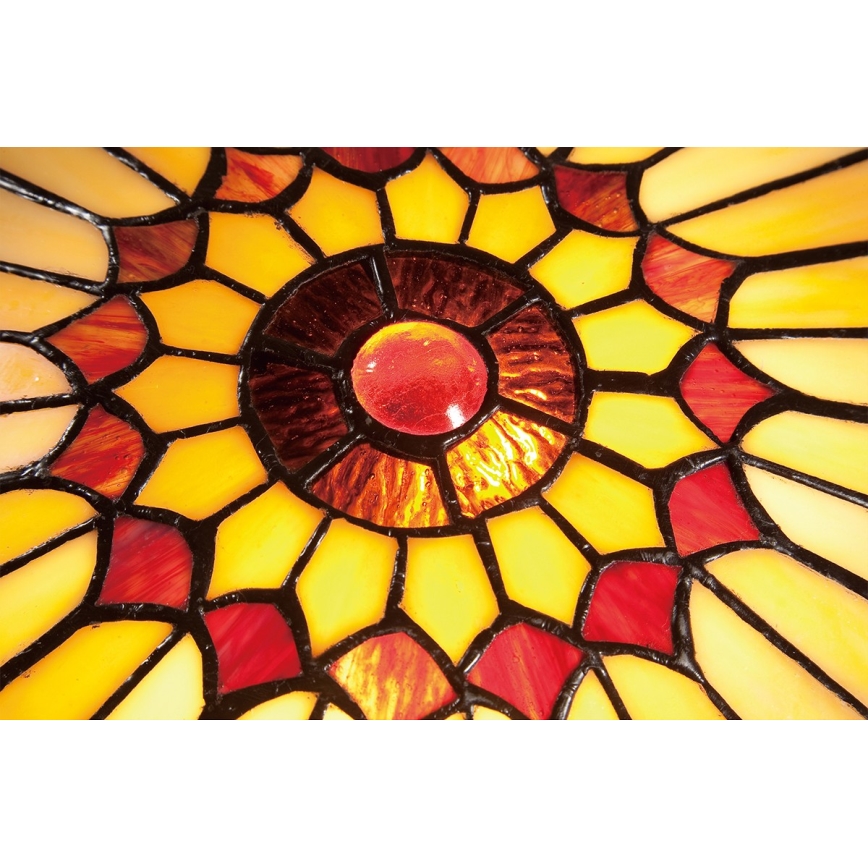 Vitrážový tienidlo svietidla zobrazuje svietiaci vzor v odtieňoch žltej a červenej, tvorený geometricky usporiadanými sklenenými dielikmi.