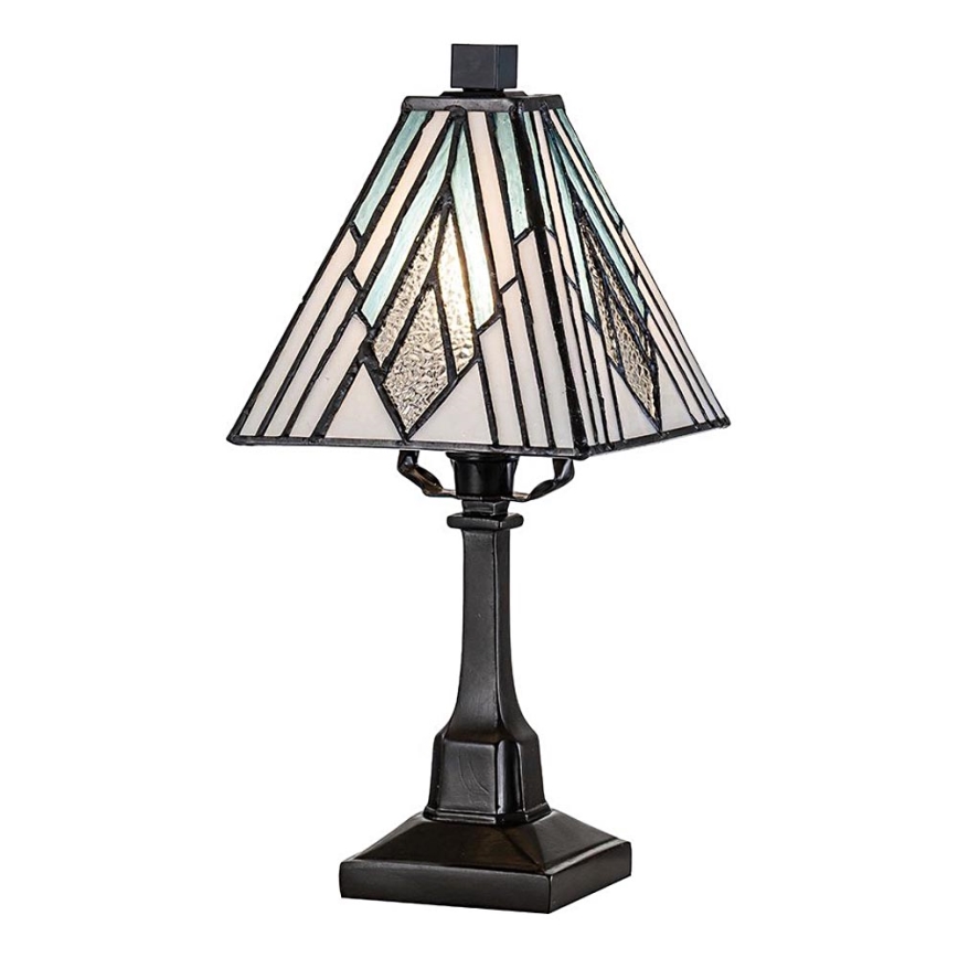 Stolová lampa s tienidlom z farebného skla, svieti, stojí na čiernom podstavci. Tienidlo je štvorcové, s geometrickým vzorom v odtieňoch bielej a svetlomodrej.
