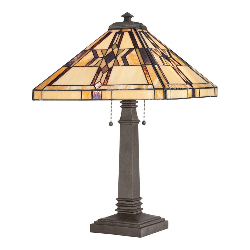 Stolová lampa s štvorcovou základňou a tienidlom z farebného skla s geometrickým vzorom stojí na bielom pozadí.