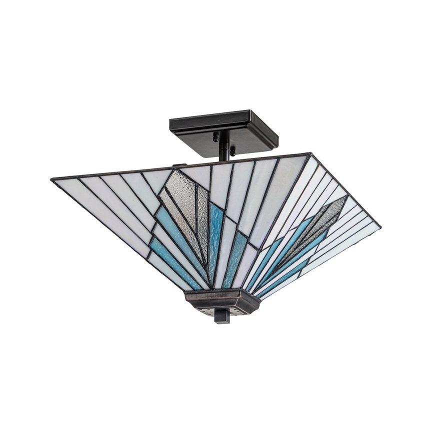 Stropná lampa s štvorcovou tienidlom zo sklenených segmentov v modro-bielej farebnej kombinácii visí zo stropu. Tienidlo má geometrický vzor. Lampa má tmavohnedý kovový podstavec.
