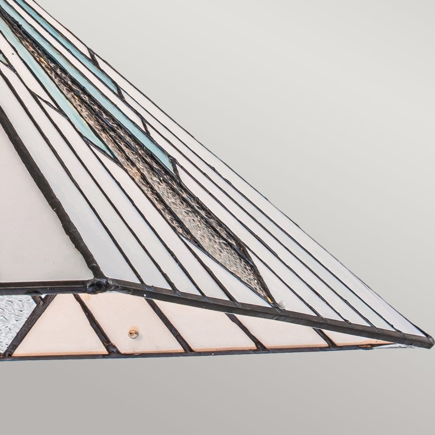 Vitrážový tienidlo ku svietidlu v tvare kužeľa je zložené z bielych a svetlomodrých sklenených častí spojených čiernou olovou. Tienidlo je umiestnené proti svetlému pozadiu.