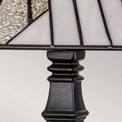 Stolová lampa s tienidlom z opálového a sivého skla stojí na tmavohnedej podstavci. Tienidlo má geometrický vzor. Podstavec má valcovitý tvar s ozdobnými ryhami.