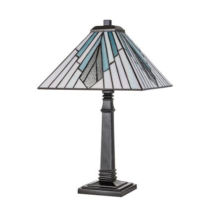 Stolová lampa s štvorcovou tienidlom z Tiffany skla v modrobielych tónoch stojí na tmavom podstavci. Lampa je osvetľovacím telesom. Biela plocha je na pozadí.