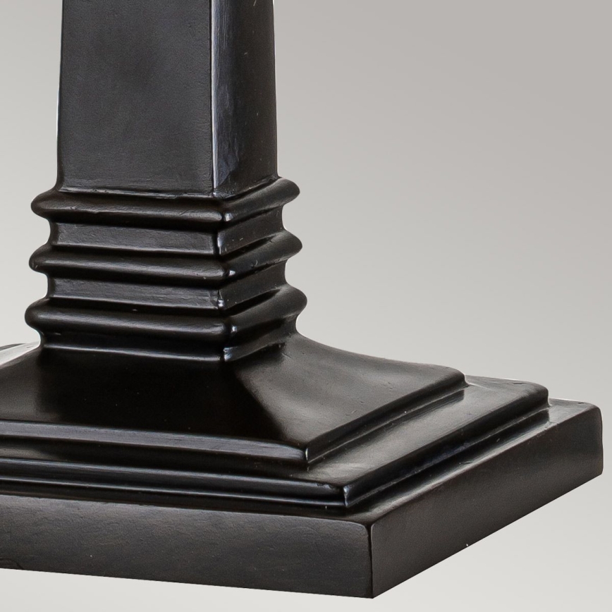 Čierny podstavec s hranatým tvarom, zložený z niekoľkých vodorovných stupňov, je umiestnený na svetlom pozadí.