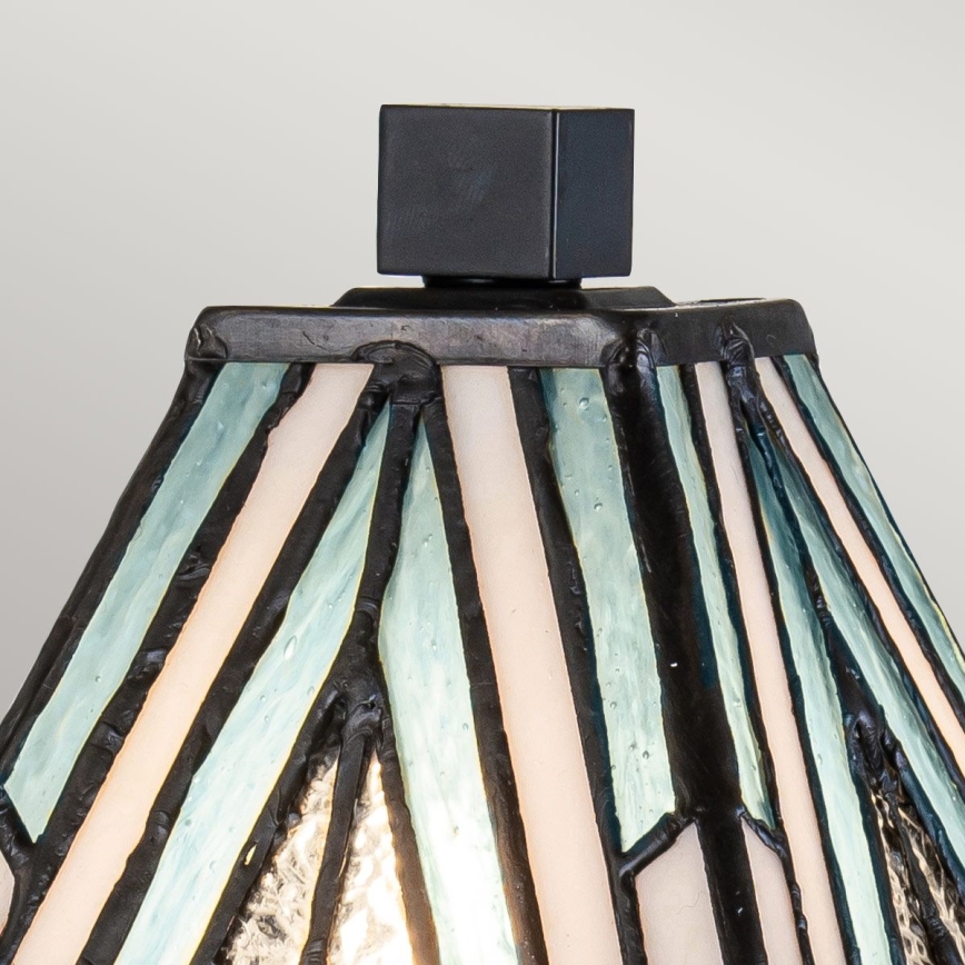 Lampa s tienidlom z farebného skla s bielymi a svetlomodrými pruhmi rozdelenými čiernou olovou, zakončeným čiernym štvorcovým vrchnákom.