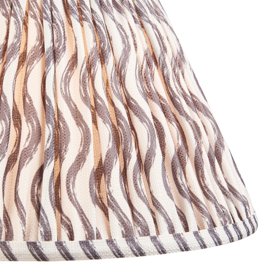 Tienidlo s vlnitým vzorom v sivej a béžovej farbe je z látky s vertikálnymi záhybmi. Spodný okraj je ozdobený pruhom s rovnakým vzorom.