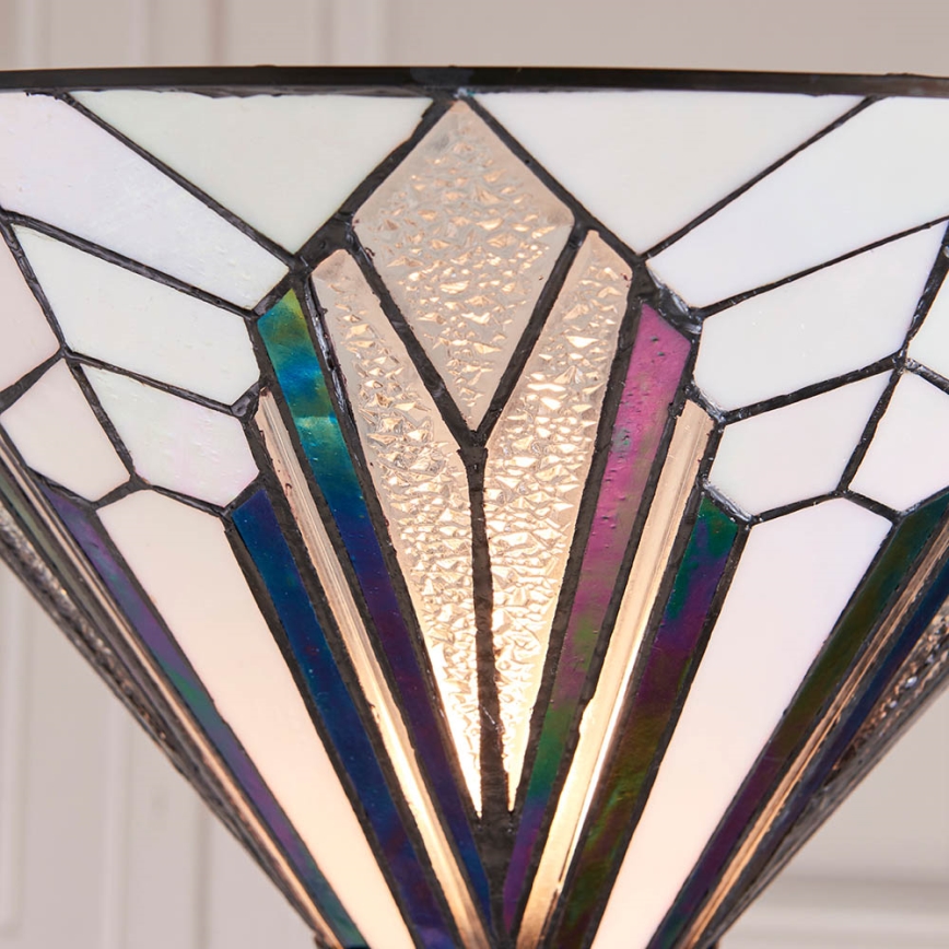 Tienidlo svietidla z vitráží svieti. Jeho tvar je kužeľovitý, s geometrickým vzorom v odtieňoch bielej, fialovej a modrej. Je osvetlené zvnútra.