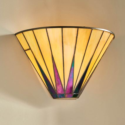 Žltá sklenená nástenná lampa s fialovými a tmavomodrými detailmi svieti na svetlej stene. Lampa má kužeľovitý tvar a je zmontovaná z mnohých menších sklenených dielov.