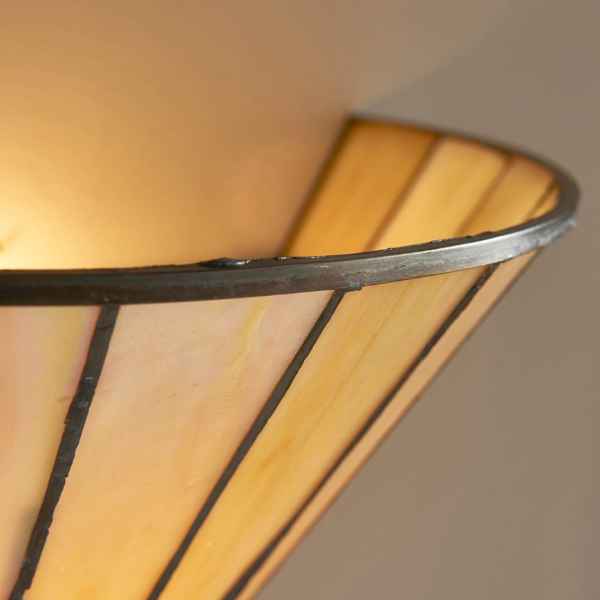 Svietidlo s kužeľovitým tienidlom zo svetložltého opálového skla a tmavohnedým kovovým lemom svieti. Tienidlo je delené vertikálnymi čiarami. Svetlo pochádza zvnútra tienidla.