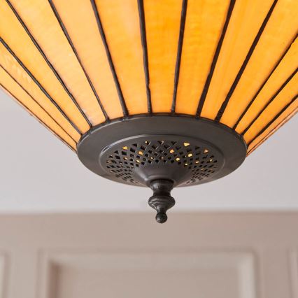 Tienidlo kužeľovitého tvaru s oranžovým tienidlom z priehľadného skla a tmavosivým kovovým spodkom je pripevnené k stropu. Spodná časť tienidla má perforovaný kovový disk s ozdobným vrcholom.