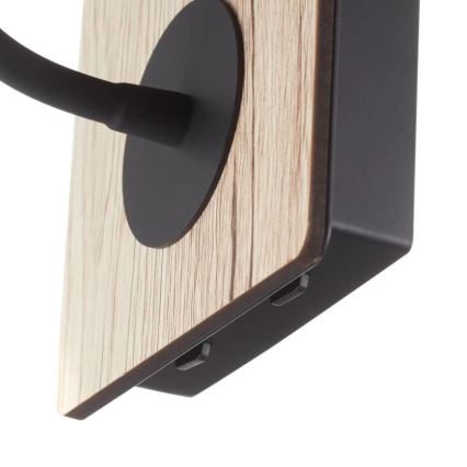 Nástenná lampa s dreveným štítkom je pripevnená na stenu. Jej ramená sú čiernej farby a sú pripojené k štítku. Na spodku sú viditeľné dva vypínače.