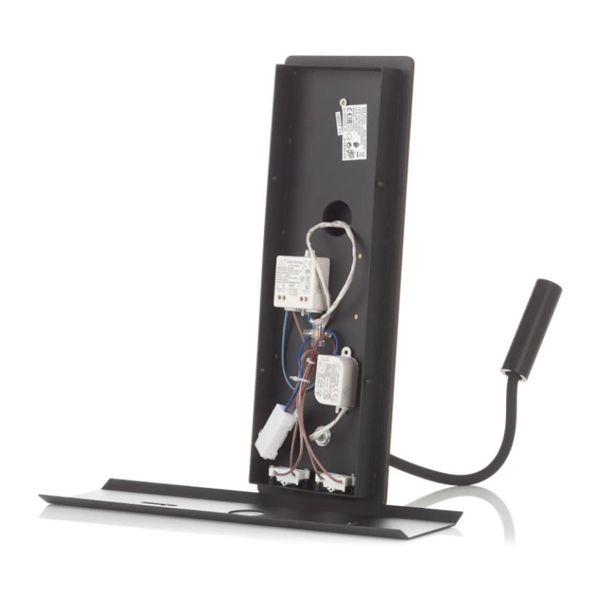 Čierna nástenná lampa s odnímateľným krytom odhaľuje vnútorné elektrické komponenty a zapojenia. Lampa má flexibilnú ramienkovú konštrukciu a je umiestnená na plochej podložke.