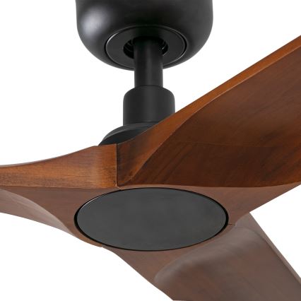 Drevený stropný ventilátor s tmavými kovovými časťami rotuje. Jeho tri hnedé lopatky majú zaoblený tvar. Ventilátor je zhotovený z dreva a kovu.