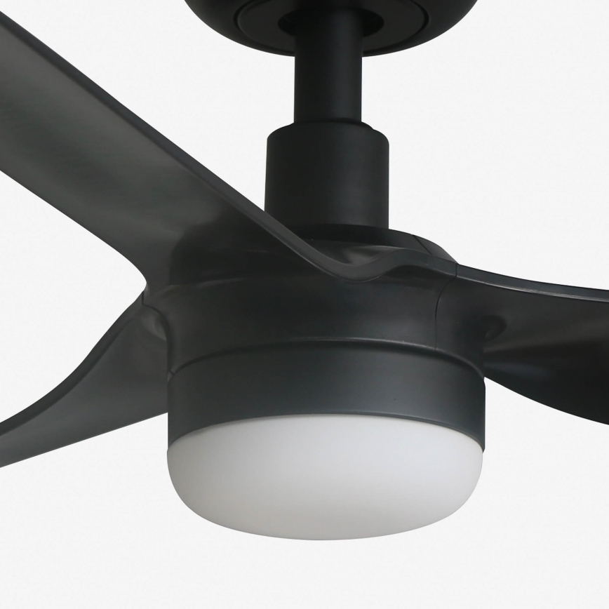 Čierny stropný ventilátor s tromi lopatkami a zabudovaným bielym svetlom. Ventilátor je pripevnený k stropu a jeho lopatky sú v pokoji. Je zobrazený na bielom pozadí.