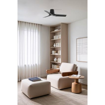 Stropný ventilátor s tromi lopatkami sa nachádza v obývacej izbe s knižnicou, kreslom a taburetkou.