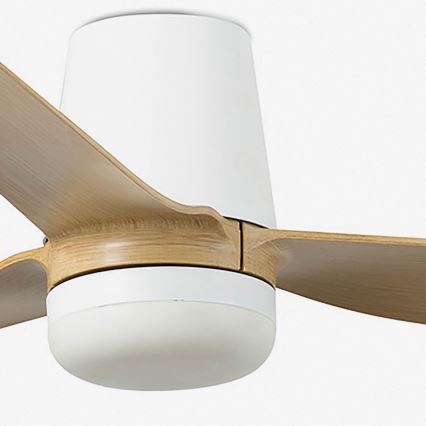 Stropný ventilátor s drevenými lopatkami a bielym krytom sa otáča. Ventilátor má zabudované svetlo. Je pripevnený k stropu.