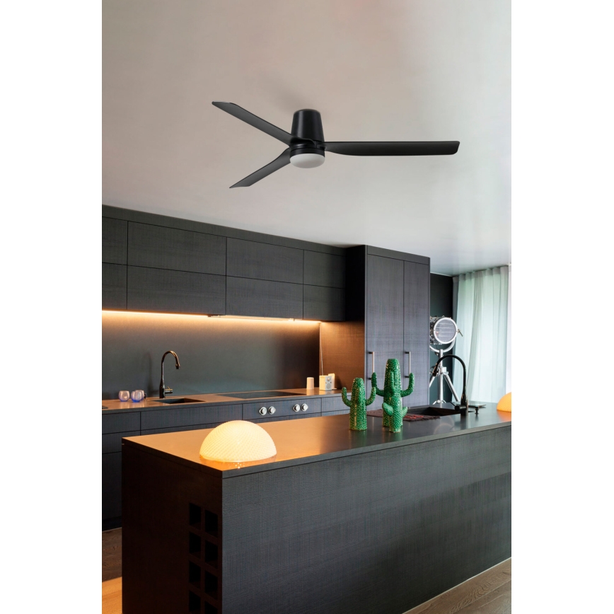 Čierny stropný ventilátor s tromi lopatkami sa otáča v modernej tmavosivej kuchyni. Kuchyňa má ostrovček s tmavou pracovnou doskou a vstavanými skrinkami.