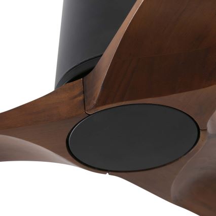 Drevený stropný ventilátor s tmavohnedými lopatkami a čiernym stredovým krytom sa otáča. Viditeľná je časť ventilátora s detailom spojenia lopatiek a stredového mechanizmu.