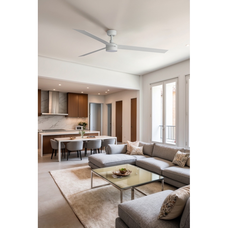Biely stropný ventilátor s troma lopatkami rotuje v modernom otvorenom priestore s obývacou izbou a kuchyňou. Obývacia izba obsahuje sivú sedačku a konferenčný stolík. Kuchyňa má ostrovček so stoličkami.