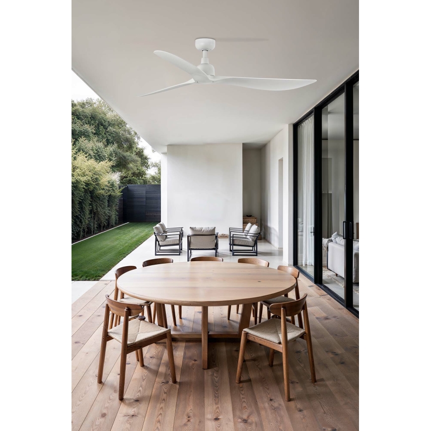 Biely stropný ventilátor s troma lopatkami rotuje v exteriéri. Nachádza sa nad okrúhlym dreveným stolom s drevenými stoličkami, na priestrannej terase s výhľadom na trávnik a záhradu.