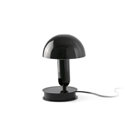 Stolová lampa s čiernym tienidlom v tvare huby stojí na čiernej podstave. Je pripojená k elektrickej sieti. Lampa je umiestnená na bielom pozadí.