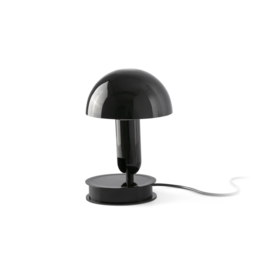Stolová lampa s čiernym tienidlom v tvare huby stojí na čiernej podstave. Je pripojená k elektrickej sieti. Lampa je umiestnená na bielom pozadí.