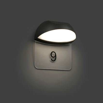 Svietidlo osvetľuje číselný štítok s číslom 9. Svietidlo je pripevnené na stenu.