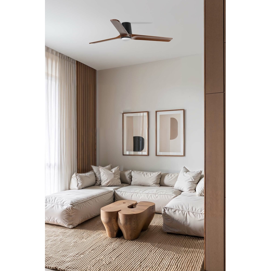 Drevený stropný ventilátor rotuje v svetlej obývacej izbe s rohovou sedačkou a dreveným konferenčným stolíkom. Izba má svetlé steny, hnedé drevené prvky a koberec.