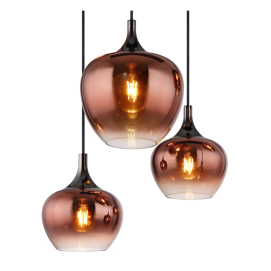 Tri medené sklenené závesné lampy s čiernymi kovovými tienidlami visia na čiernych kábloch. Lampy sú rôznych veľkostí a majú prechod farieb od tmavej medi k svetlejšej. V každej lampe je vidieť žiarovku.