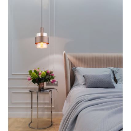 Svietidlo visí v spálni. Je dvojdielne, kovové v zlatej farbe, s priehľadnou sklenenou časťou. Nachádza sa nad nočným stolíkom s kvetmi a vedľa postele s posteľnou bielizňou.