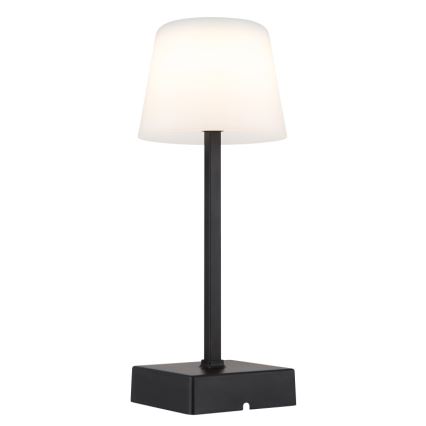 Stolová lampa svieti. Má čierny kovový stojan a biely tienidlo v tvare zrezaného kužeľa. Je umiestnená na bielom pozadí.
