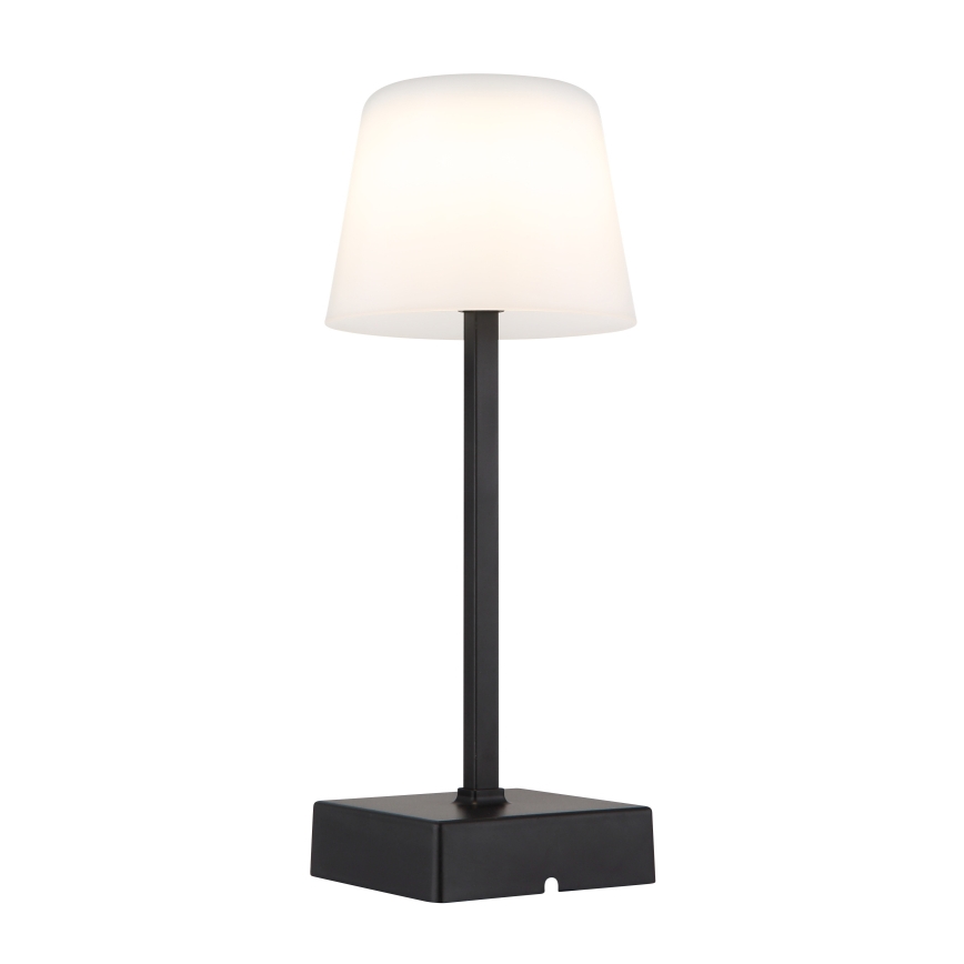 Stolová lampa svieti. Má čierny kovový stojan a biely tienidlo v tvare zrezaného kužeľa. Je umiestnená na bielom pozadí.