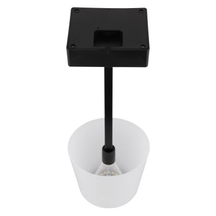 Solárna lampa s čiernym štvorcovým panelom na vrchu a bielym difúzorom v tvare valca dole, osvetľuje LED dióda. Čierna tyč spája obe časti.