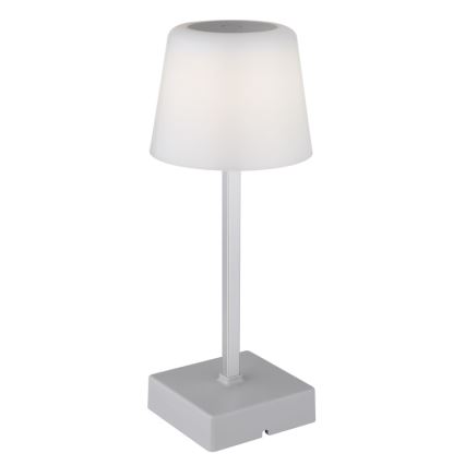 Stolná lampa svieti. Má sivý kovový stĺpik, biely tienidlo a sivú štvorcovú základňu. Lampa je samostatne stojaca na bielom pozadí.