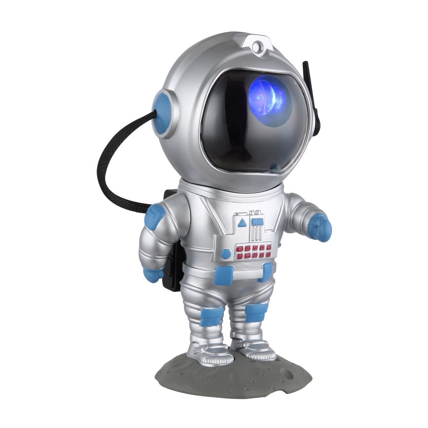 Strieborná figúrka astronauta s modrým svetielkom v prilbe stojí na sivej podložke imitujúcej mesačný povrch. Astronautova prilba má anténu.