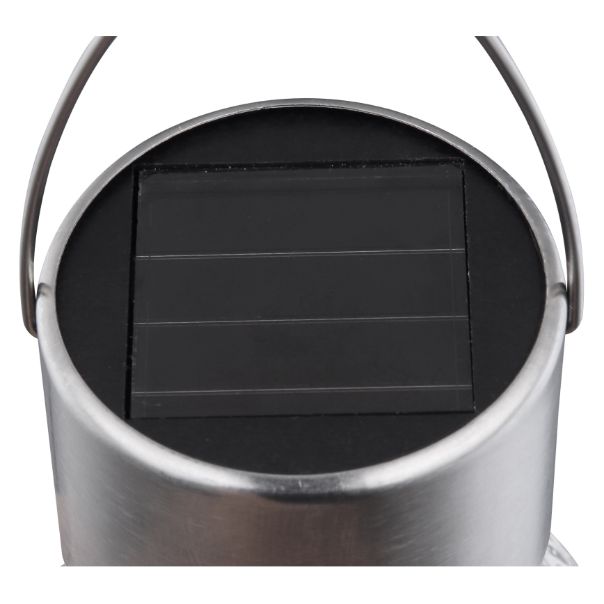 Solárny panel absorbuje svetlo. Je umiestnený na vrchu kovovej nádoby s úchytkou. Nádoba vyzerá ako lampa.