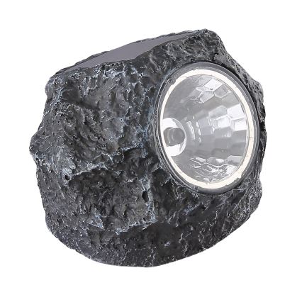 Solárny kameň svieti. Jeho povrch imituje štruktúru skaly. Svietidlo je umiestnené na bielom pozadí.