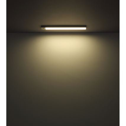 LED pásik osvetľuje stenu. Pásik je pripevnený na strope v tmavej miestnosti. Svetlo pásika sa šíri po stene.
