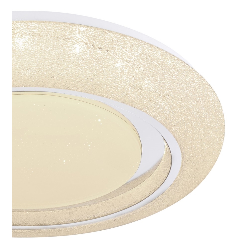 Svietidlo svieti. Jeho oválny tvar má vrstvený dizajn s pieskovou štruktúrou vonkajšieho kruhu a svetložltým vnútorným difúzorom. Je umiestnené na bielom pozadí.