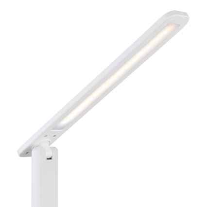 Biela stolná lampa s LED osvetlením svieti. Rameno lampy je výsuvné a otočné. Lampa je umiestnená na bielom podstavci.