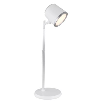Stolná lampa s bielym tienidlom a strieborným stojanom svieti. Lampa je umiestnená na bielom podstavci na bielom pozadí.