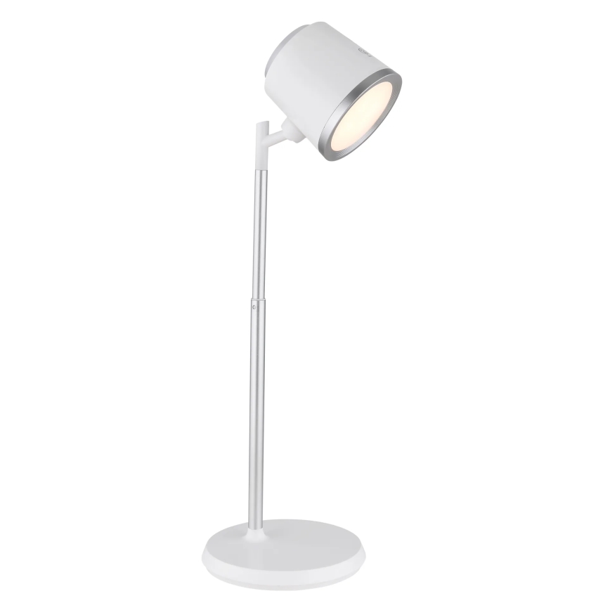 Stolná lampa s bielym tienidlom a strieborným stojanom svieti. Lampa je umiestnená na bielom podstavci na bielom pozadí.
