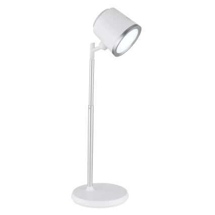 Stolová lampa s bielym tienidlom a strieborným stojanom svieti. Je umiestnená na bielom podstavci na bielom pozadí.