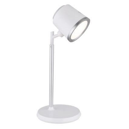 Stolná lampa s bielym tienidlom a strieborným stojanom svieti. Je umiestnená na bielom pozadí.