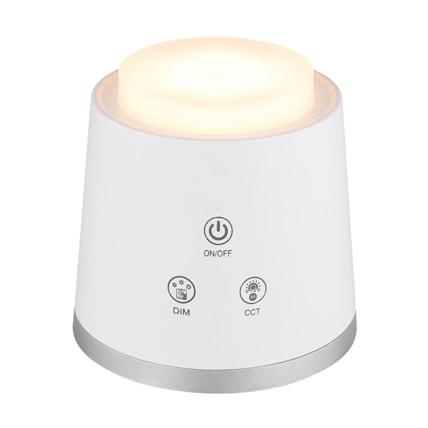 Biela stolová lampa svieti. Na spodnej časti sú tlačidlá: ON/OFF, DIM, CCT. Lampa má strieborný okraj.
